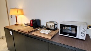 Una cocina americana con microondas, tostadora, cafetera y una lámpara sobre una encimera de madera.