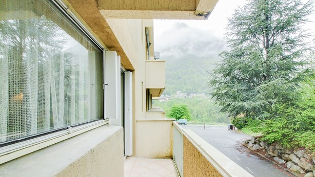 A balcony with a view of a mountain and a car parked on the street.