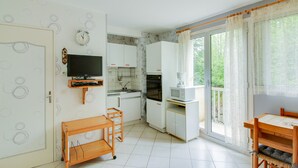A compact kitchen with a television, microwave, and dining area with a table and chairs.