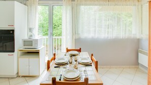A dining area with a table set for four, a microwave, a coffee maker, and a cabinet with a red handle.
