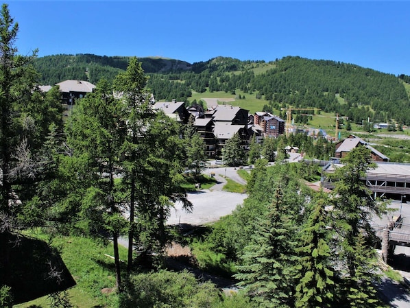 A mountainous resort area with lodge buildings, dense forest, and a clear sky.