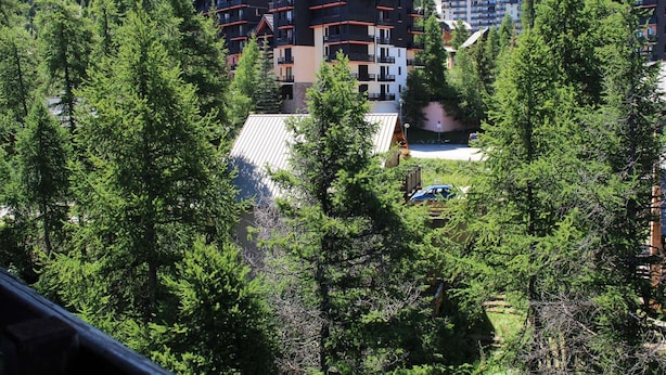 A multi-story hotel with balconies, surrounded by dense forest.