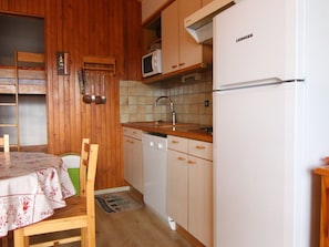 A compact kitchen with wooden cabinets, a white refrigerator, a microwave, and a sink. - Cozy Studio for 4 in L'Alpe d'Huez - Ski-in/Ski-out, South Balcony, Near Amenities (Huez)