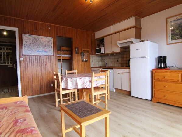Une cuisine compacte dotée de meubles en bois, d’un four à micro-ondes, d’un réfrigérateur et d’une table à manger avec des chaises.