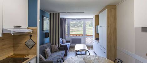 A compact kitchen with a dining area, a sofa, and a view of the outdoors.