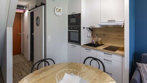 Una cocina compacta con armarios blancos, encimera de madera, horno integrado y microondas.