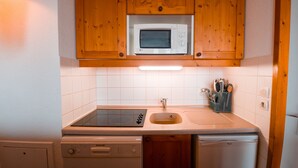 Une cuisine compacte avec des meubles en bois, un four à micro-ondes, un évier et un lave-vaisselle.