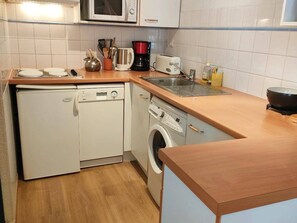 A compact kitchen with a dishwasher, washing machine, microwave, and a toaster.