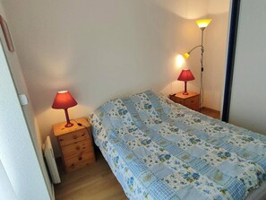 A bedroom with a bed, two bedside tables, and two lamps.