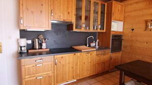 A wooden kitchen with cabinets, a coffee maker, a sink, and a stove.