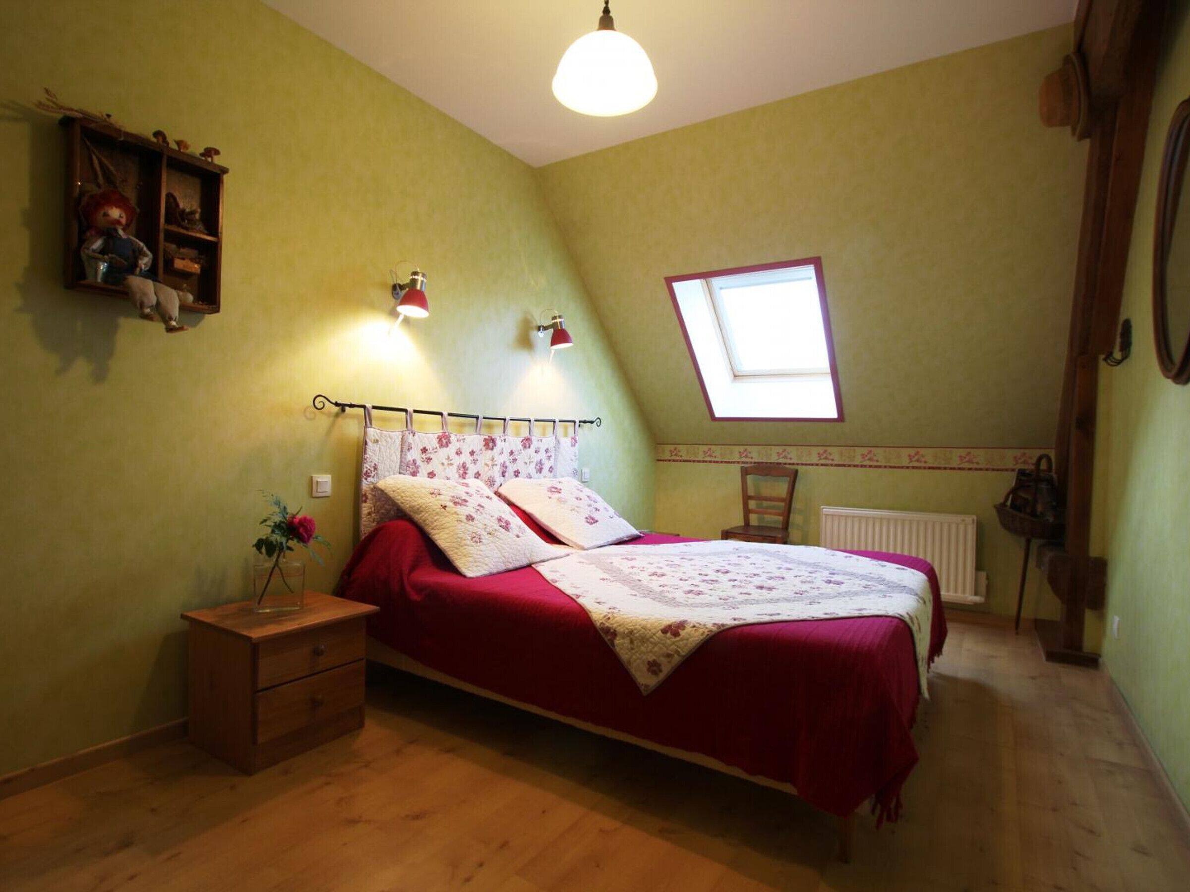 A bedroom with a bed, a nightstand, a dresser, a window, and a radiator.