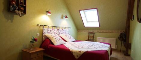 A bedroom with a bed, a nightstand, a dresser, a window, and a radiator.