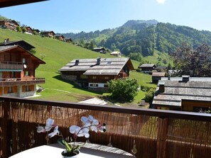 A wooden chalet with a balcony, surrounded by green hills and a clear sky. - Center, 2 rooms + mezzanine, balcony, elevator, 6 beds (Le Grand-Bornand)