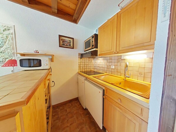 A compact kitchen with wooden cabinets, a microwave, a sink, and a dishwasher. - Center, 2 rooms + mezzanine, balcony, elevator, 6 beds (Le Grand-Bornand)