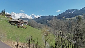 Eine Berglodge mit Blick auf schneebedeckte Gipfel und ein bewaldetes Tal.