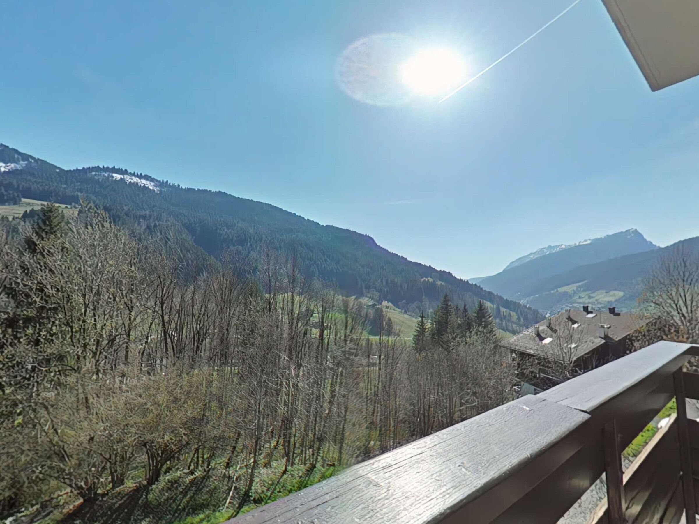 A mountain landscape with a clear sky and a wooden balcony railing.