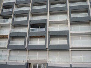 Ein mehrstöckiges Gebäude mit modernem architektonischen Design, das eine Reihe von rechteckigen Fenstern und Balkonen aufweist.