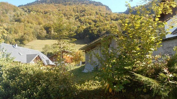 A rural landscape with a mountain in the background, a stone house, and a building with a sloped roof. - Cozy 3-Room Duplex with Balcony, Parking, Near Ski Lift, Sleeps 4 (Cauterets)