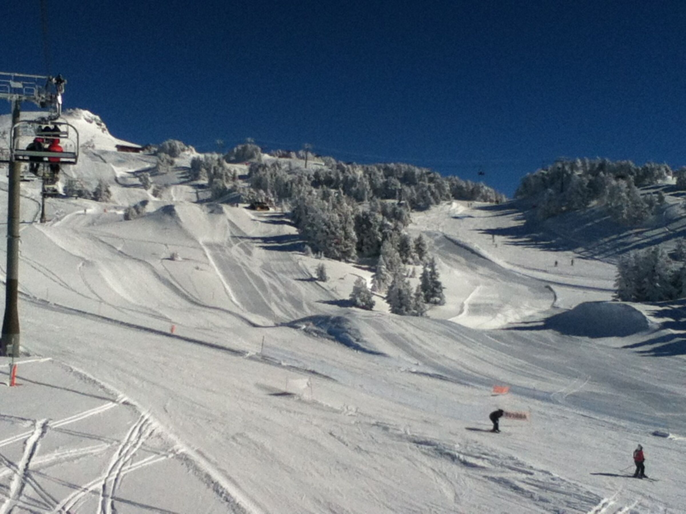 Una pista de esquí nevada con un telesilla y árboles.