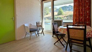 Une pièce avec un plafond en bois, une porte verte, une table avec des chaises et une vue sur la verdure à l’extérieur.