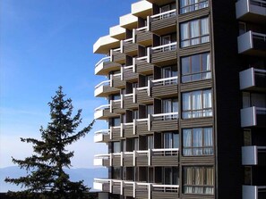 Un edificio residencial de varios pisos con balcones, ventanas amplias y cielo despejado.