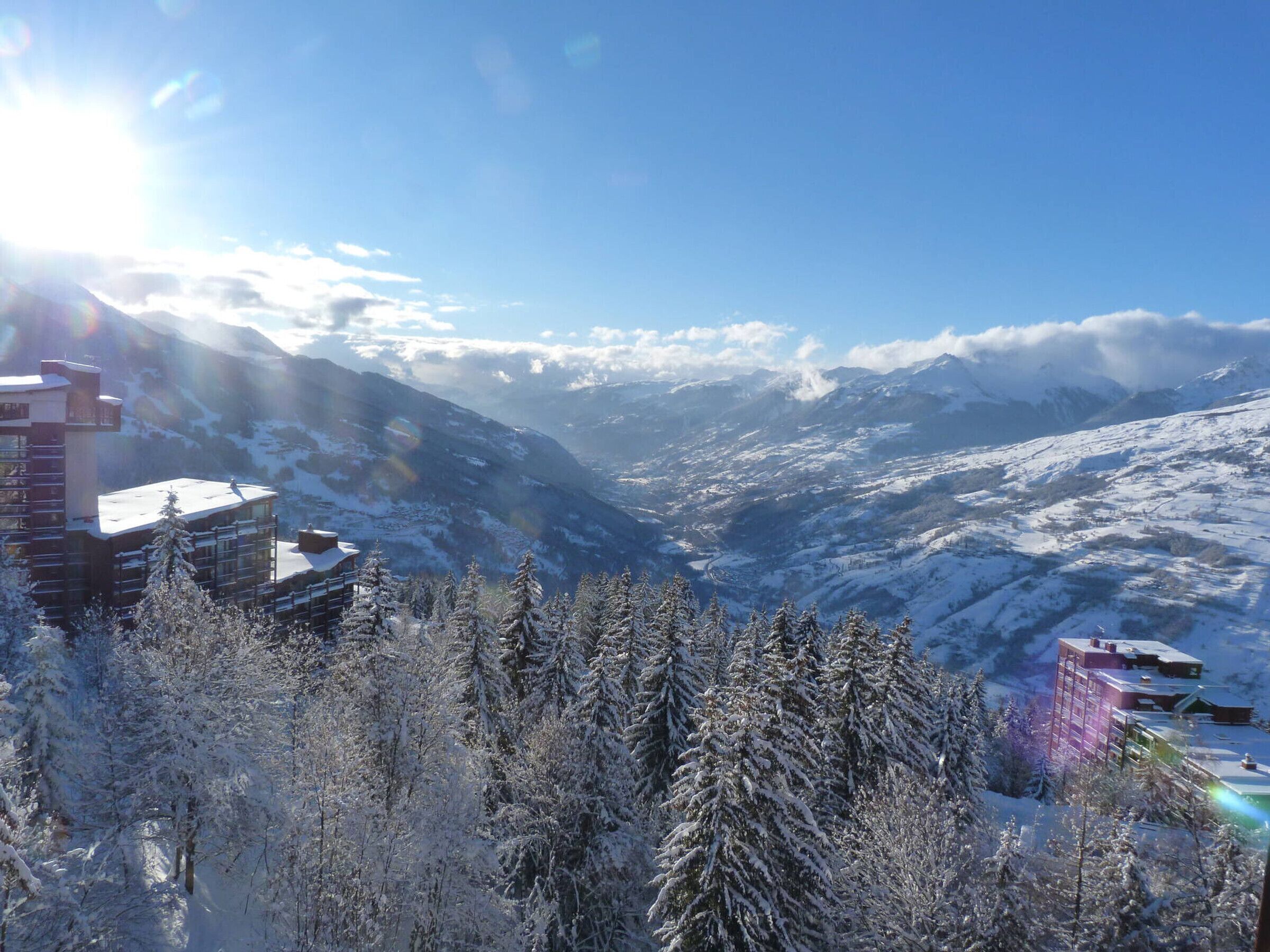 Eine verschneite Berglandschaft mit Gebäuden und Bäumen.