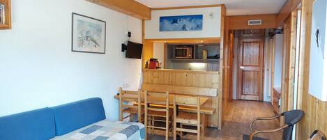 Cozy living space with a kitchenette, sofa, dining table, and microwave.