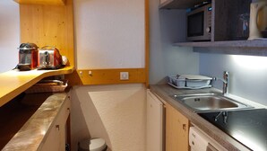 A compact kitchen with wooden cabinets, a microwave, a sink, and a toaster. - 2-room apartment 6 ppl, pets allowed, southwest balcony, close to slopes (Les Arcs 1800)