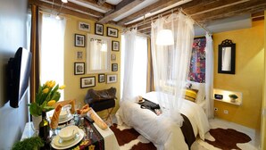 A cozy bedroom with a bed, bedside table, and a wall adorned with framed pictures.