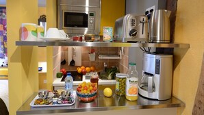 A kitchen with a microwave, toaster, coffee maker, and various food items on the counter.