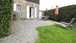 A stone building with a gravel driveway, a grassy area, and outdoor seating.