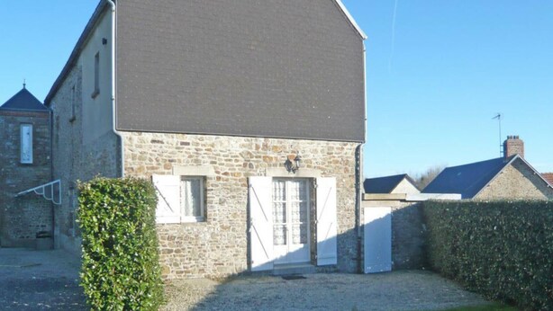A stone building with a dark roof, a small door, and a window.