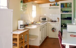 A compact kitchen with a coffee maker, microwave, and washing machine.