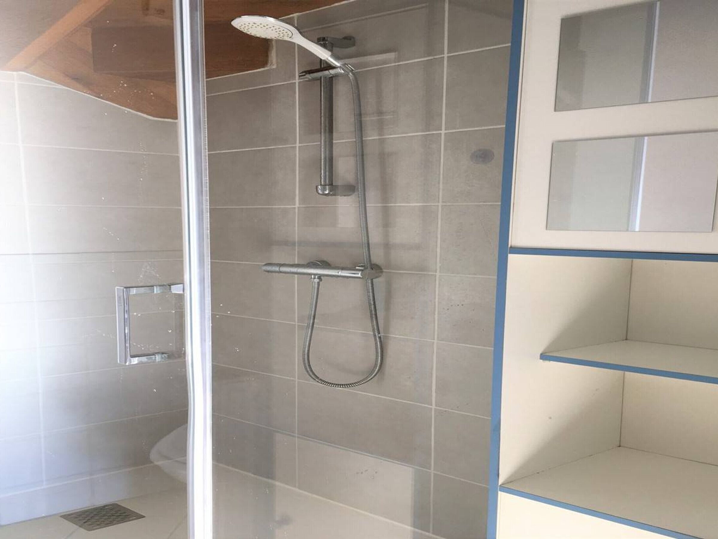 A shower with a handheld showerhead and a wall-mounted faucet.