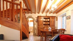 A wooden staircase leading to an upper floor, a dining area with a wooden table and chairs, and a kitchen with wooden cabinets.