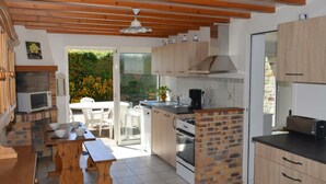 A compact kitchen with wooden cabinets, a built-in oven, and a dining area with a table and chairs.
