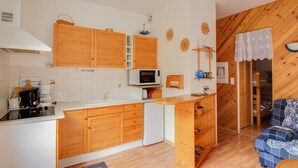 Une cuisine de taille réduite, dotée de meubles en bois, d’un four à micro-ondes et d’un évier.