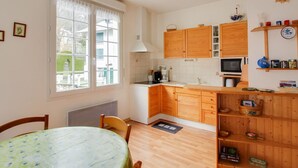 Une cuisine compacte dotée de meubles en bois, d’un four à micro-ondes et d’un coin repas avec une table et des chaises.