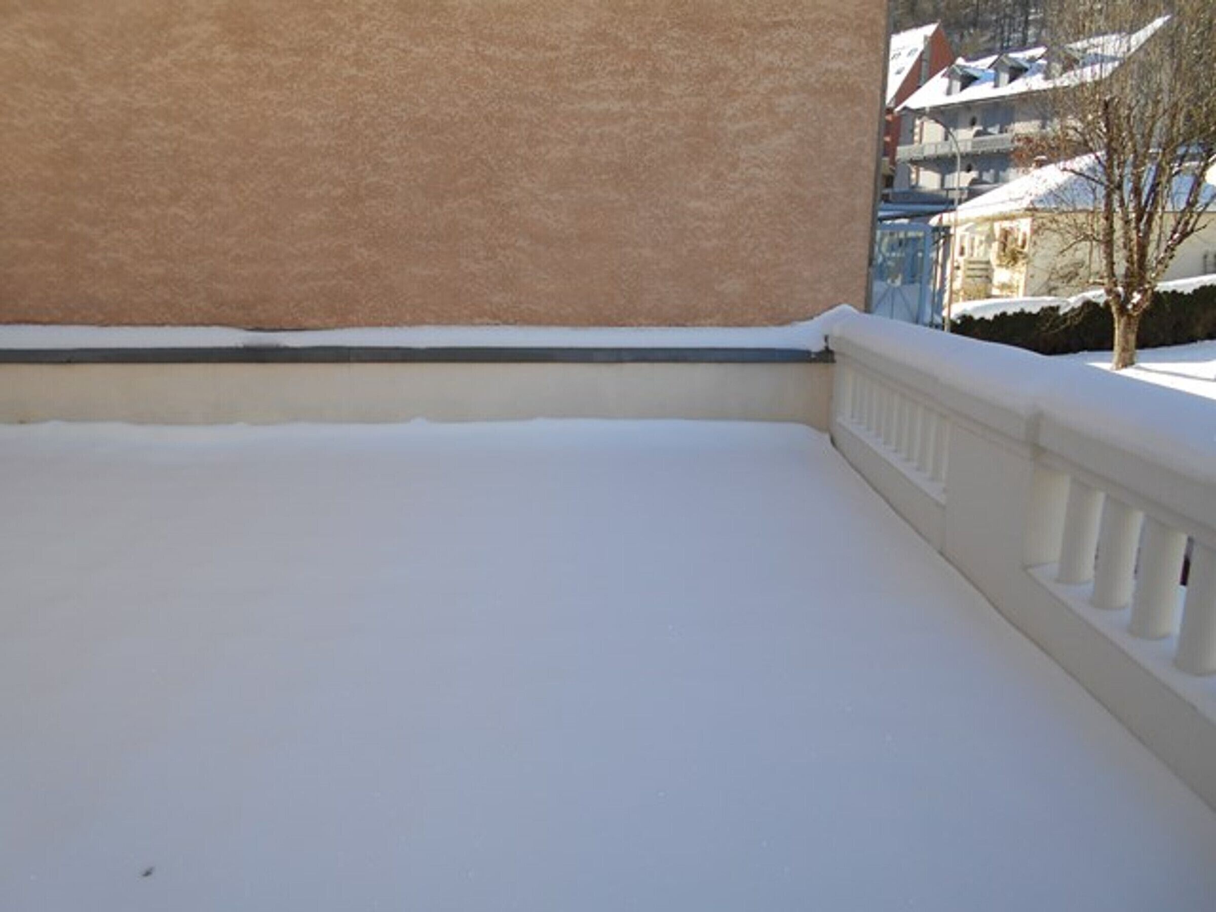 En snötäckt balkong med ett vitt räcke.