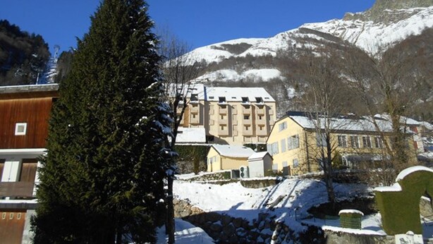 Un bâtiment dont le toit est recouvert de neige, entouré d’arbres et de montagnes.