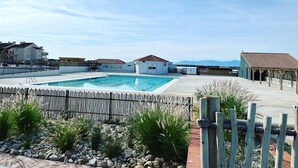 A swimming pool with a wooden fence, surrounded by a landscaped garden with rocks and plants. - Apt 4 rooms, 8 ppl, pool, tennis, parking included - Port Barcarès (Port Barcarès)