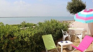 A beachside seating area with a table, chairs, and a colorful umbrella. - Apt 4 rooms, 8 ppl, pool, tennis, parking included - Port Barcarès (Port Barcarès)