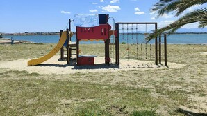 A playground with a slide and climbing structures near a beach with a clear sky. - Apt 4 rooms, 8 ppl, pool, tennis, parking included - Port Barcarès (Port Barcarès)