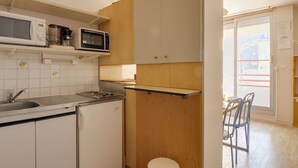 Une cuisine de taille réduite équipée d’un four à micro-ondes, d’une cuisinière, d’un évier et d’armoires en bois.