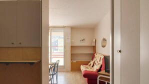 Une petite pièce compacte comprenant un coin cuisine, un canapé, une table à manger avec des chaises et un fauteuil roulant.