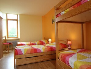Cozy bedroom with a bunk bed setup, featuring a window, wooden chair, and small table.