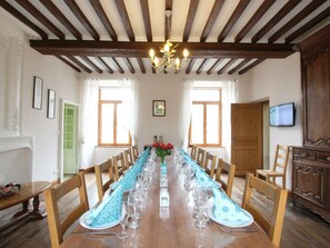 Enjoy meals in this dining room with a long table, chandelier, and fireplace.