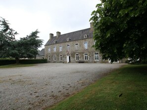 A large stone building with multiple windows and a gravel courtyard.