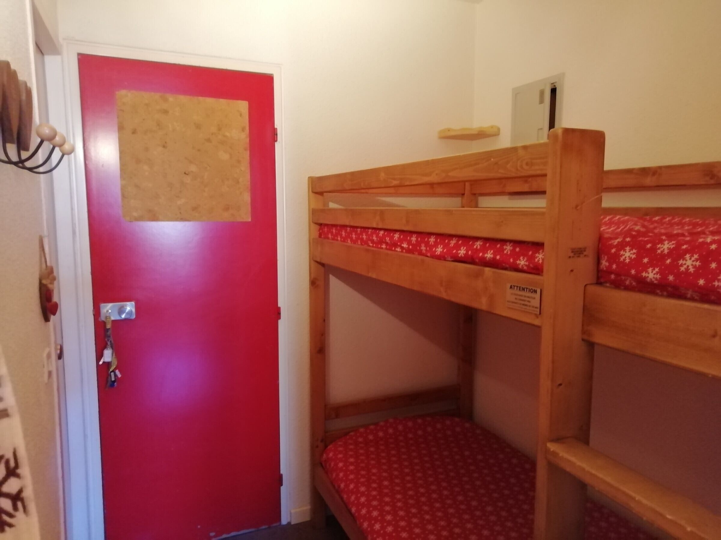 A bunk bed with a red mattress and a wooden headboard.