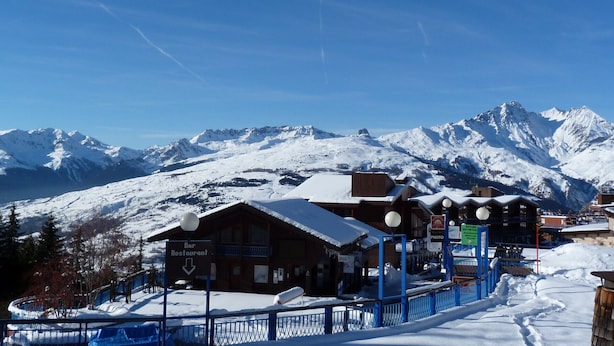 Une ville de montagne enneigée, avec un bar-restaurant et une vue sur les sommets environnants.